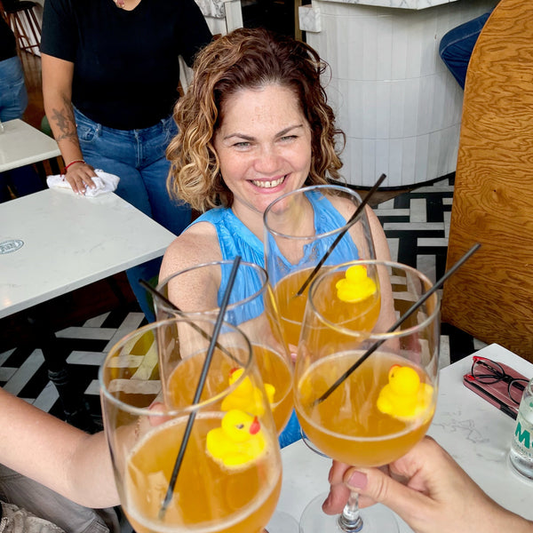 Woman laughing at a restaurant table with drinks.
