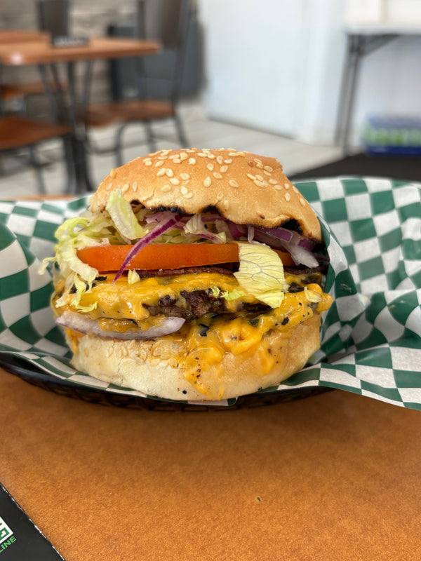 Loaded cheeseburger on a checkered paper-lined plate.