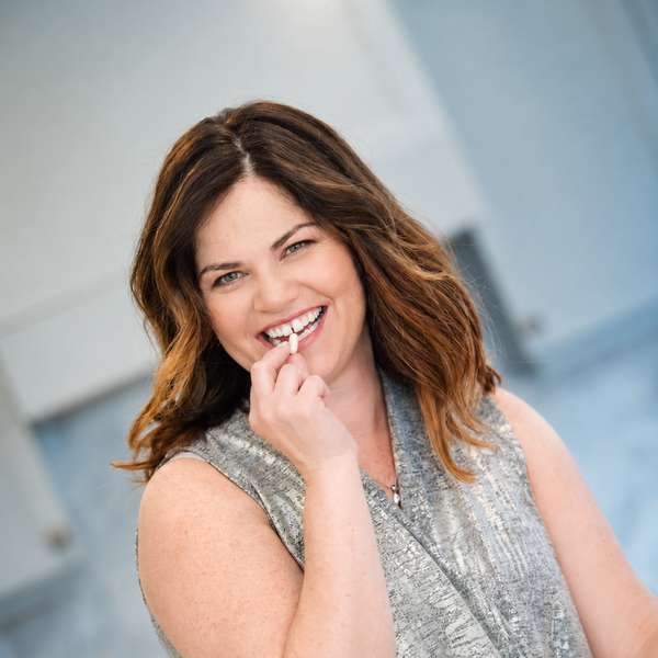 Woman smiling and taking a capsule before a meal.