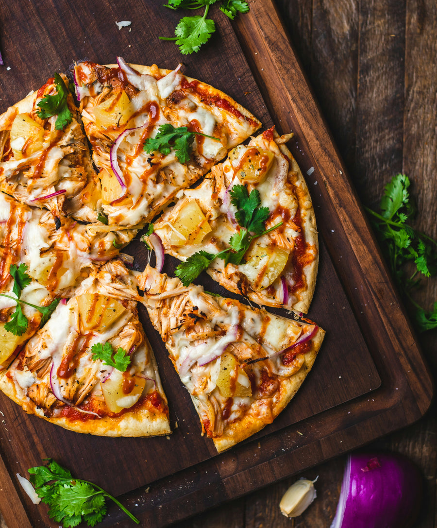 Sliced pizza topped with chicken, pineapple, and cilantro.